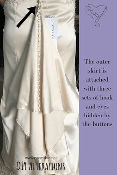 the dress is attached with three sets of hooks and eyes hidden by the buttons on the skirt