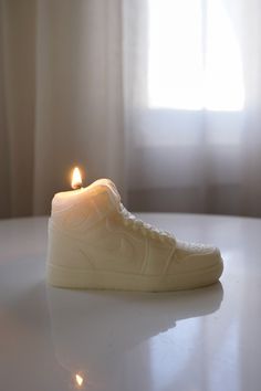 a white sneaker with a lit candle in the middle on top of a table