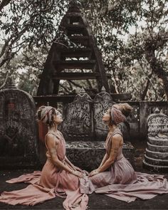 two women sitting on the ground in front of some tombstones