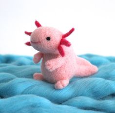 a pink stuffed animal sitting on top of a blue blanket