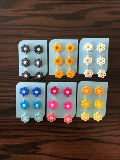 six pairs of flower earrings are shown in different colors and sizes on a wooden surface