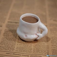 a cup of hot chocolate sitting on top of a news paper next to a newspaper