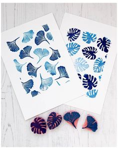 two cards with blue and pink leaves on them next to some other paper cut outs