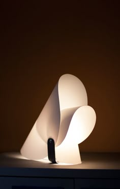 a white lamp sitting on top of a table next to a black drawer with drawers