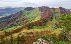 the mountains are covered in colorful trees and green grass, with small houses on each side