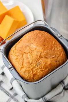 a loaf of bread sitting in a pan next to some buttered cheese cubes