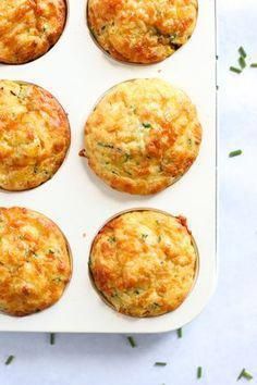 several muffins in a white tray with green sprigs on the side