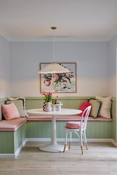 a white table and some pink chairs in a room with green paneling on the walls