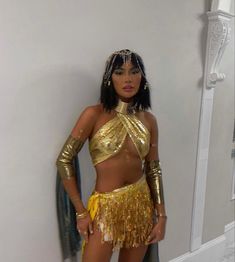 a woman in a gold outfit standing next to a mirror with her hands on her hips