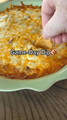 a person dipping a piece of food into a bowl with the words game - day dip above it