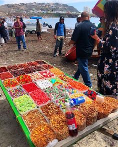 a table with many different types of candies on it and people standing around in the background