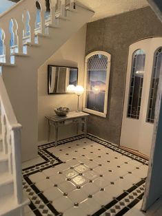 an entry way leading to a white staircase with black and white tiles on the floor