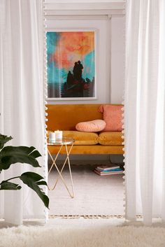 a living room with a yellow couch and white curtains