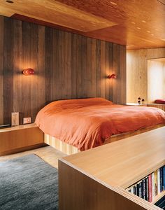 a bed sitting in a bedroom next to a book shelf with books on top of it