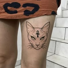 a woman's thigh with a cat and cross tattoo on her left side leg