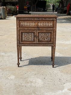 an old wooden table with intricate carvings on the top and bottom, sitting in front of a building