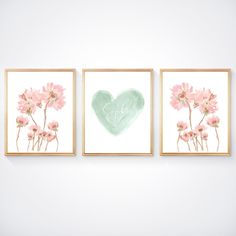 three pink flowers are hanging on the wall in front of a heart shaped sign that says love