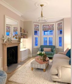 a living room filled with furniture and a fire place in front of two windows covered in blinds