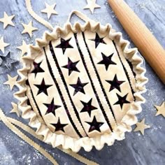 an uncooked pie with stars on it next to a rolling pin