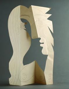 a paper sculpture with two faces cut out of it's sides and the other side is