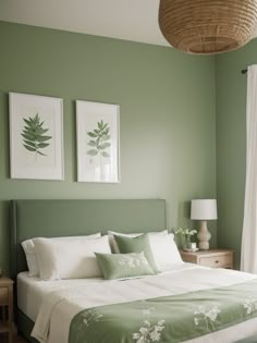 a bedroom with green walls and white bedding, two framed pictures on the wall