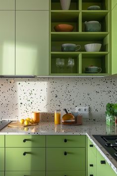 a kitchen with green cupboards and white counter tops, filled with food items such as lemons