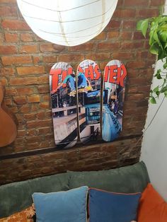 three skateboards mounted to the side of a brick wall next to a bed with pillows on it