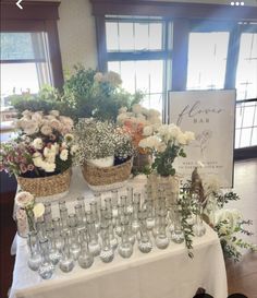 a table topped with lots of glasses filled with flowers