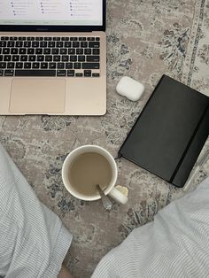 an open laptop computer sitting on top of a bed next to a cup of coffee