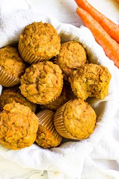 carrot muffins in a white bowl next to fresh carrots