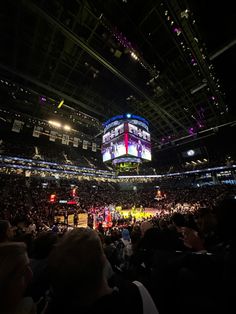 an arena filled with lots of people watching a basketball game in the middle of it