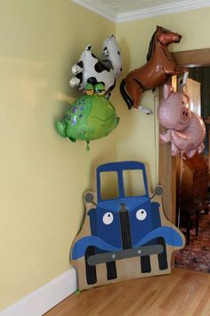 some balloons are hanging on the wall near a toy car and farm animal balloon bouquets