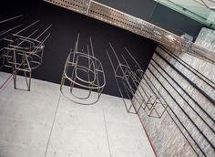 three metal sculptures sitting on top of a white tiled floor next to a black wall