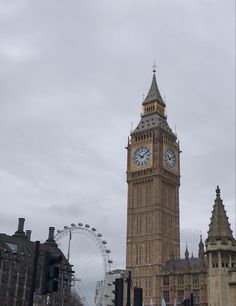 the big ben clock tower towering over the city of london with ferris wheel in the background