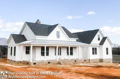 a large white house sitting on top of a dirt field