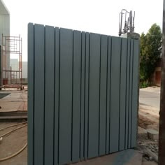 a large metal fence sitting on top of a cement ground next to a building under construction