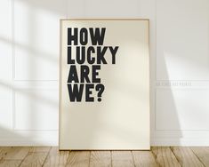 a poster with the words how lucky are we? on it in front of a white wall