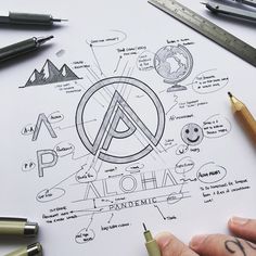 a person holding a pen and drawing on top of a piece of paper with various symbols