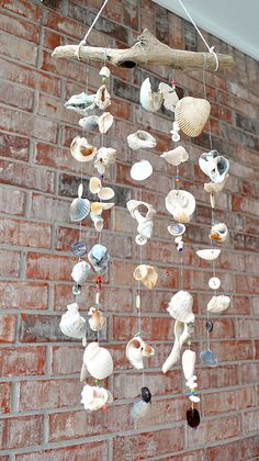 a wind chime with shells hanging from it's sides next to a brick wall