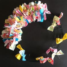 a close up of a wreath made out of small bows on a black surface with one ribbon tied to the side