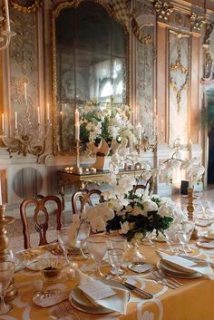 a dining room table set up with white flowers and place settings for formal dinner guests