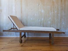 a wooden bench with a mattress on it in front of a wall and wood floor