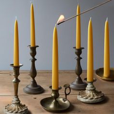 candles are lined up on a table with one lit candle in between them and the other turned off