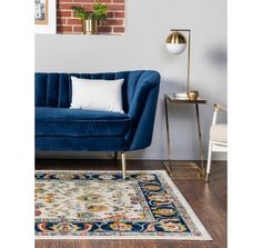 a living room with a blue couch, rug and gold accents on the floor next to a brick wall