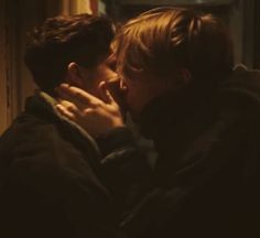 two people kissing each other in front of a window with the light shining on them