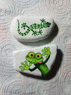 two rocks painted with green and white designs, one has a frog on it's back