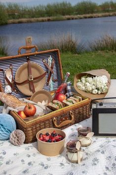 an open suitcase sitting on top of a picnic table next to a basket filled with food