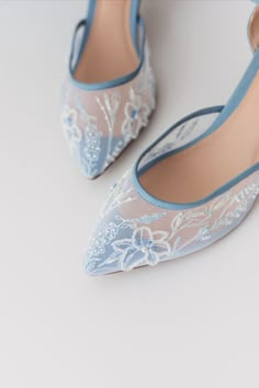 a pair of blue high heel shoes with white lace on the toes and heels are shown