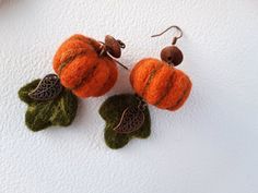 two small pumpkins with leaves on them are hanging from earwires that have been made out of felt