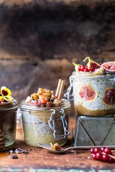 three jars filled with different types of food on top of a wooden table next to other items